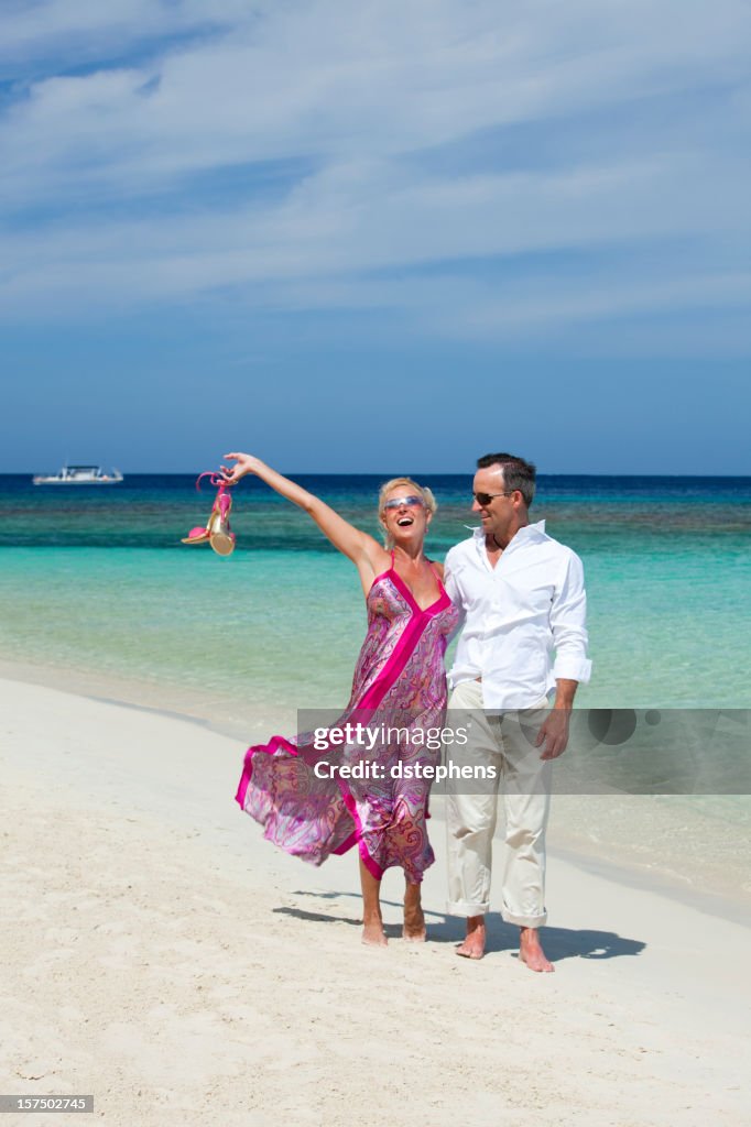 Relaxed adult couple walking along tropical beach