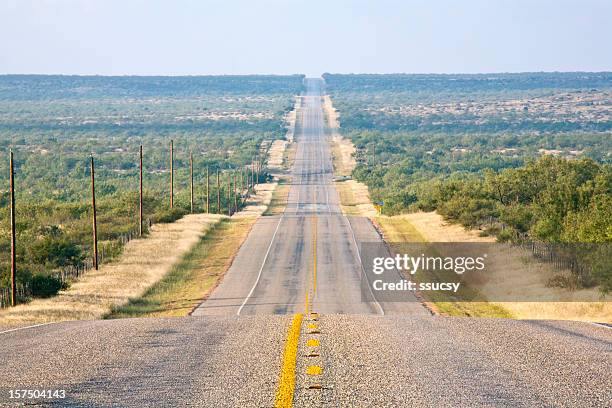 rural country road, long and straight, undulating to the horizon - texas road stock pictures, royalty-free photos & images