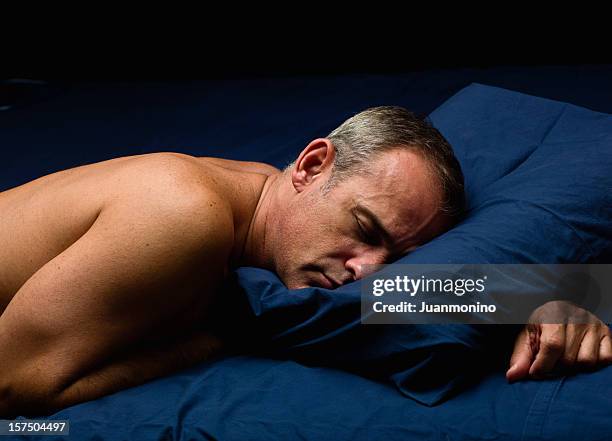 homme dormir sur son ventre sur blue literie - allongé sur le devant photos et images de collection
