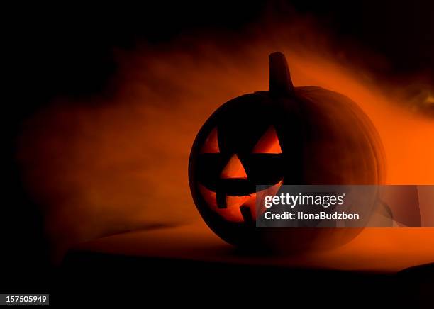 a scary halloween pumpkin in smoke  - halloween lantern stock pictures, royalty-free photos & images