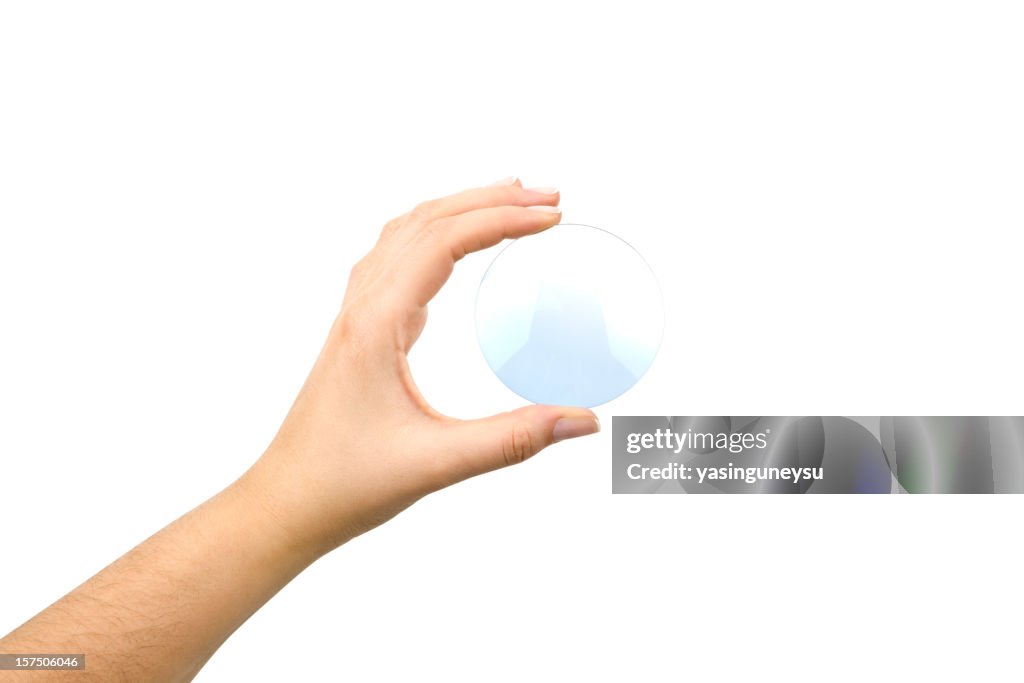 Hand holding an eyeglass lens without the glasses on white