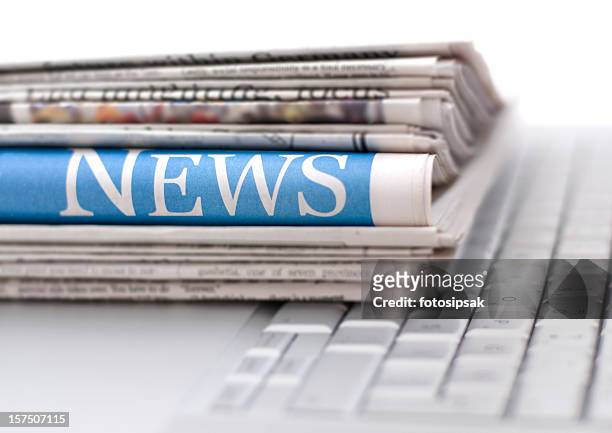 stack of newspapers resting on laptop keyboard - newspaper stack stock pictures, royalty-free photos & images