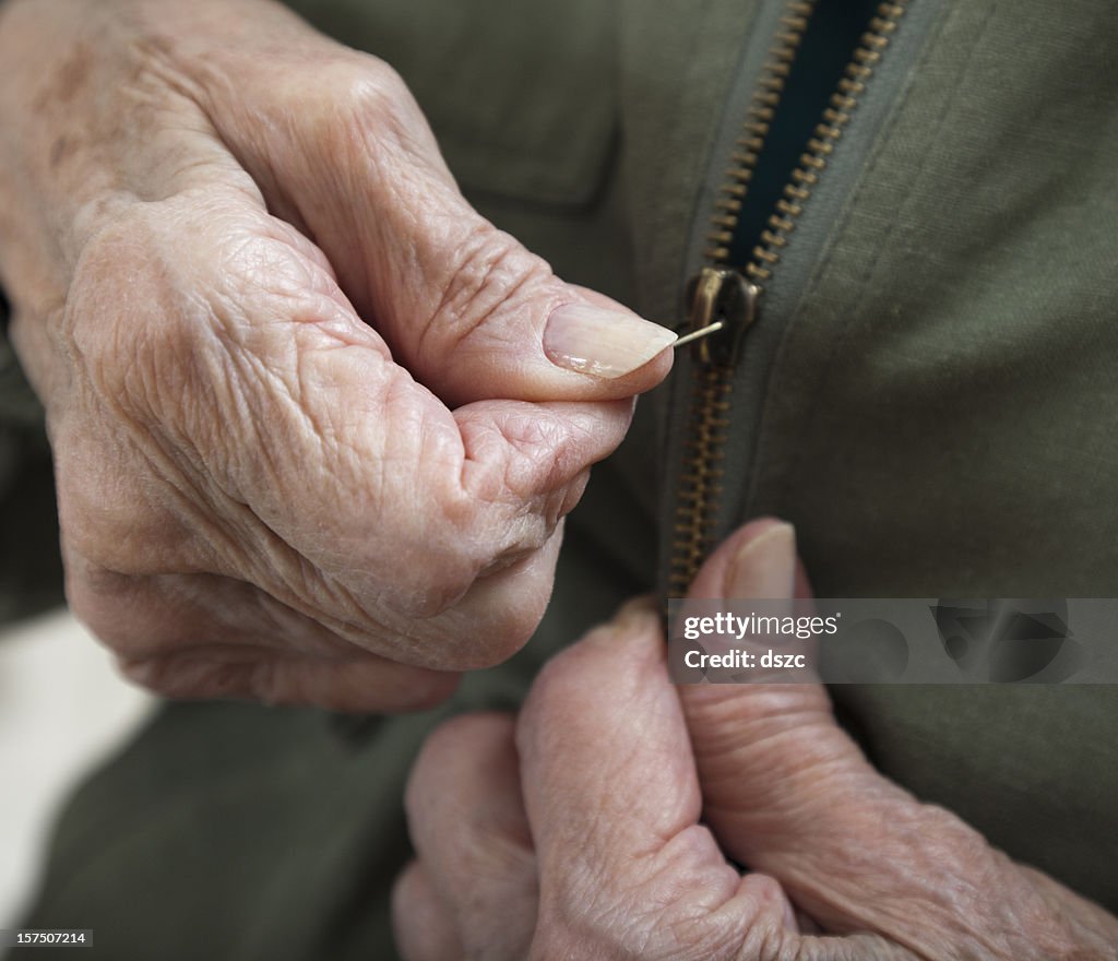Senior woman arthritis hands zipping zipper on jacket