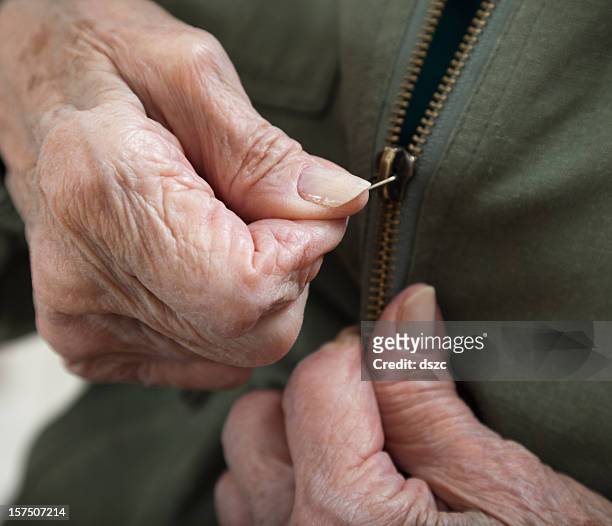 senior woman arthritis hands zipping zipper on jacket - zipper stock pictures, royalty-free photos & images