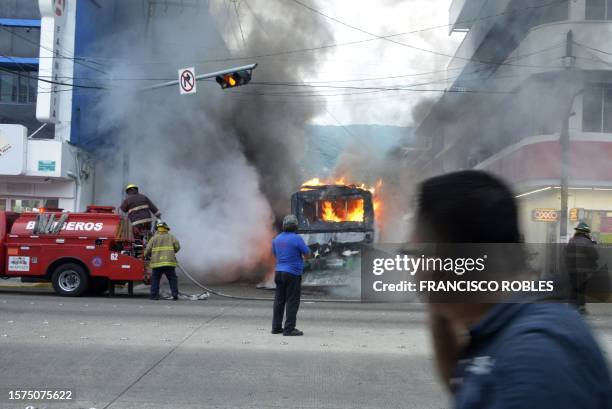 Firefighters work to extinguish a burning vehicle in Acapulco, Guerrero State, Mexico, on August 2, 2023. Armed men set fire to 12 cars in different...