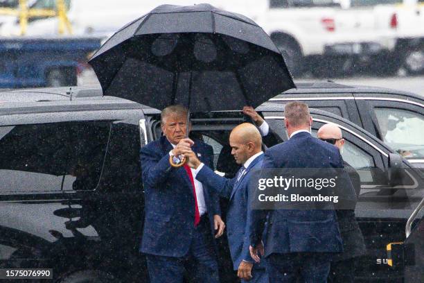 Former US President Donald Trump, left, is handed an umbrella from Walt Nauta, personal aide to former US President Donald Trump, before departing on...