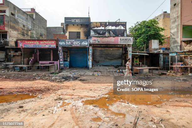 Haryana police personnel walking in front of burned shops at Ambedkar chowk in Sohna after the communal violence. Communal clashes broke out in the...