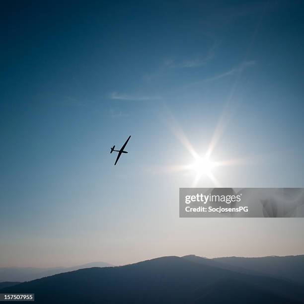 lone glider flies to the sun, mountain panorama and sky - zweefvliegtuig stockfoto's en -beelden