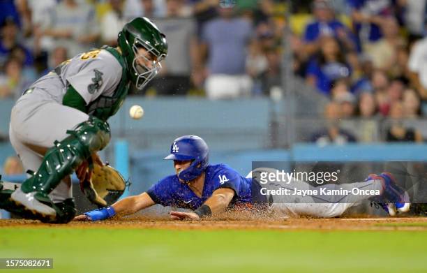 Austin Barnes of the Los Angeles Dodgers beats the throw to Shea Langeliers of the Oakland Athletics to score a run in the sixth inning at Dodger...
