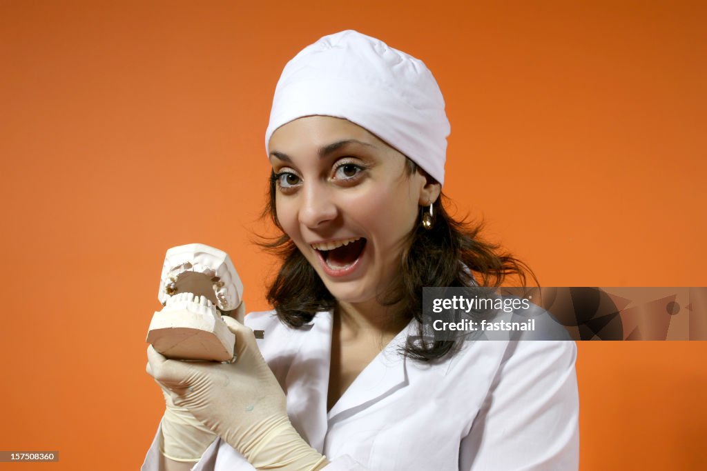 Jolie dentiste à denture sur un fond orange