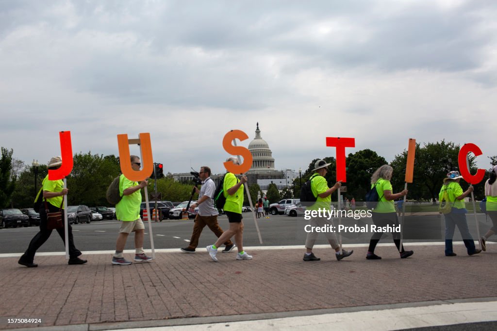 Demonstrators holding a JUSTICE sign, stand outside of the...