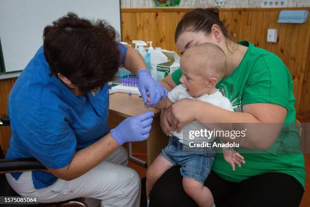 Healthcare personnel takes a blood sample from a boy in a classroom at a local school where doctors from Kiev Children's Hospital examine patients in...