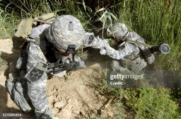 Handout released by the US Army 14 September 2007 shows Sgt. Steven Calhoun assists in pulling an Alpha Battery Soldier out of an irrigation ditch...