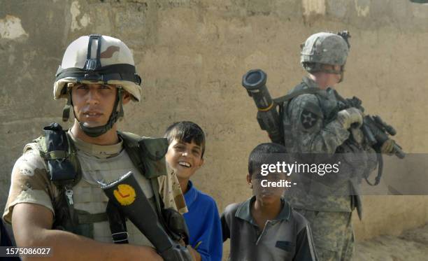 Handout released by the US Army 14 September 2007 shows an Iraqi army soldier flanked by two boys as a US Soldier assigned to Alpha Battery provides...