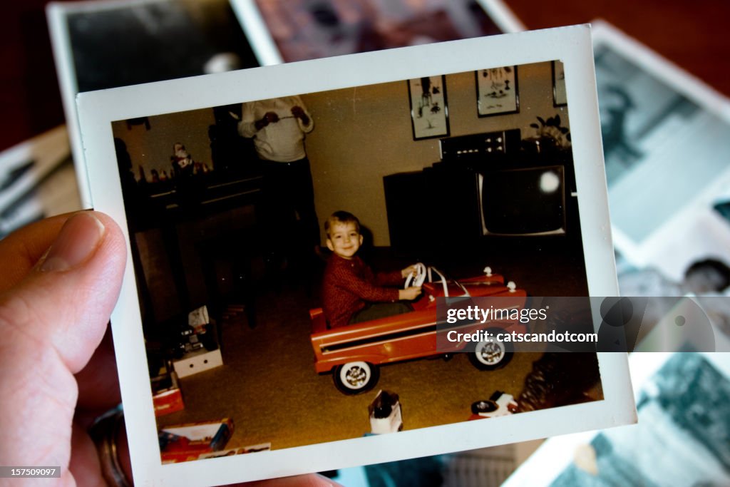 Hand holds Vintage photograph of boy in pedal car