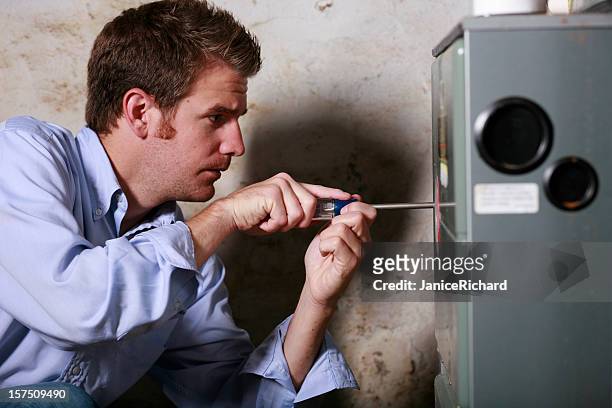 image of a man working on a furnace with a screwdriver - furnace & duct stock pictures, royalty-free photos & images