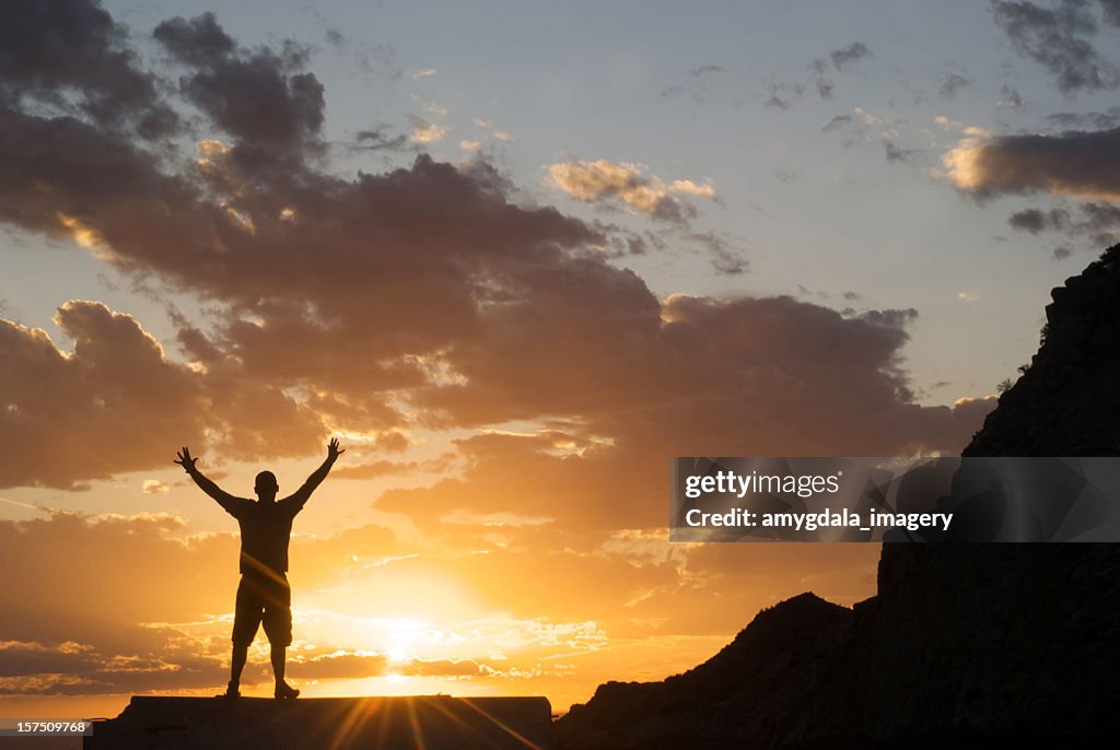Silueta hombre alzar los brazos en el cielo al atardecer