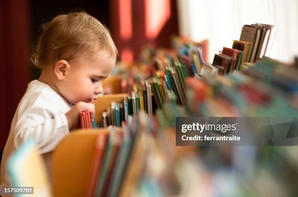 kleines mädchen in der bibliothek - toddler stock-fotos und bilder