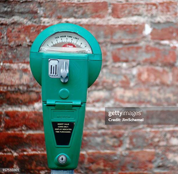 a bright green parking meter on a brick background - parking meter stock pictures, royalty-free photos & images