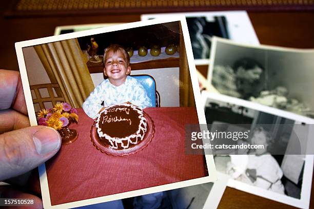 hand holds vintage photograph of child and birthday cake - memories stock pictures, royalty-free photos & images