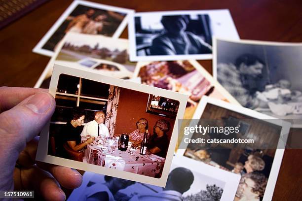 hand holds vintage photograph of parents and grandparent couple - human body part fotos stockfoto's en -beelden