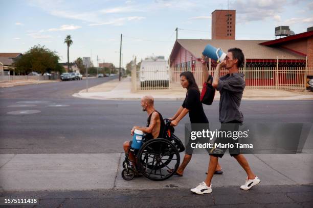 Cue Ball and Roni , who are both homeless, make their way toward a market amid the city's worst heat wave on record on July 24, 2023 in Phoenix,...