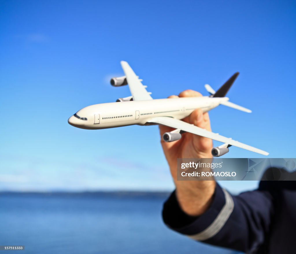 Pilota con aereo giocattolo contro il cielo blu