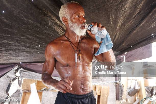 Rick White drinks water while cooling down in his tent in a section of the 'The Zone', Phoenix's largest homeless encampment, amid the city's worst...