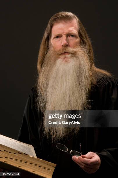 bearded man wearing scholar's robe holding book/bible-looking at camera - long beard stock pictures, royalty-free photos & images