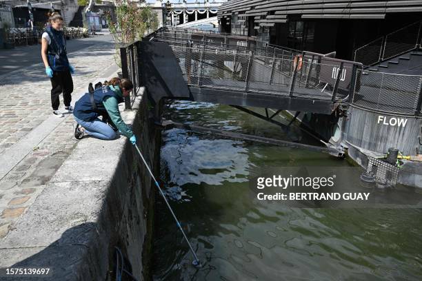 An employee of the company Fluidion collects a sample of water from the Seine to analyse its composition ahead of the 2024 Paris Olympics, near the...