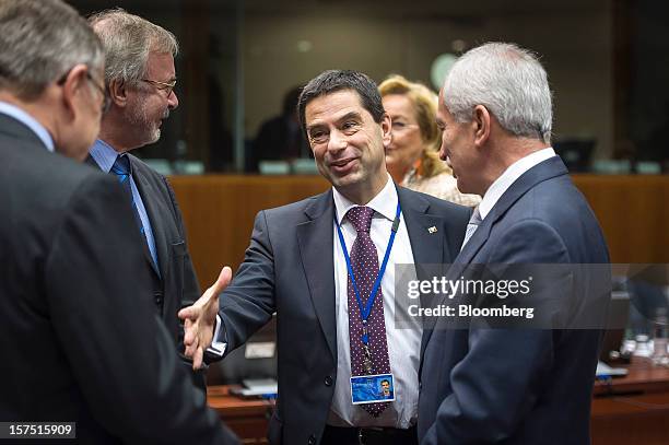 Vitor Gaspar, Portugal's finance minister, center, greets Klaus Regling, chief executive officer of the European Stability Mechanism, left, Werner...