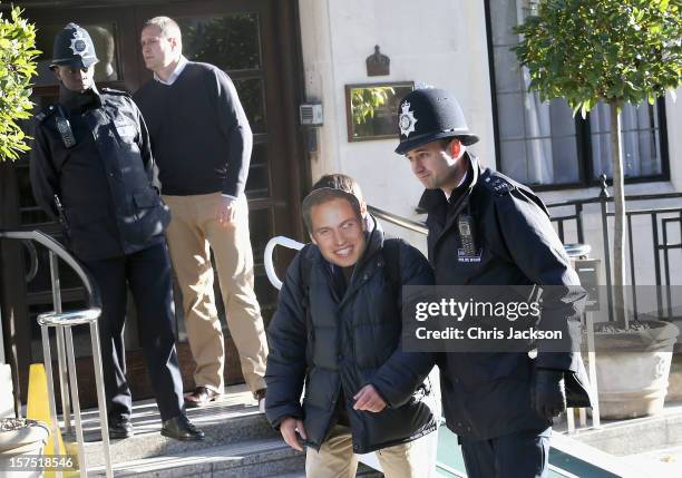 Man wearing a Prince William, Duke of Cambridge mask is escorted away by a police officer from the King Edward VII Private Hospital on December 4,...