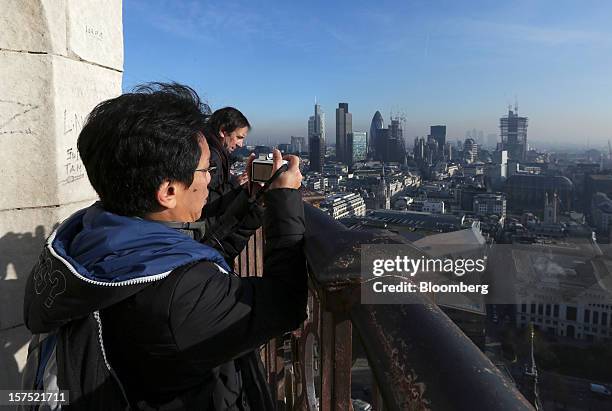 Tourist takes a photograph of the financial district from the top of St Paul's Cathedral in London, U.K., on Friday, Nov. 30, 2012. U.K. Banks have...