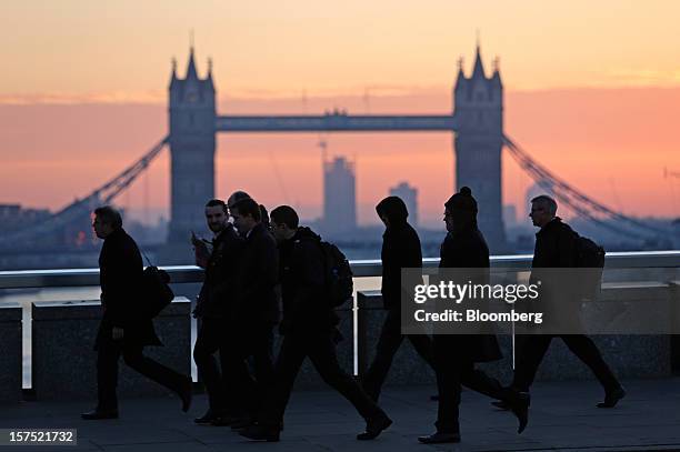 Commuters walk across the River Thames on London Bridge, past Tower Bridge, in London, U.K., on Friday, Nov. 30, 2012. U.K. Banks have become more...