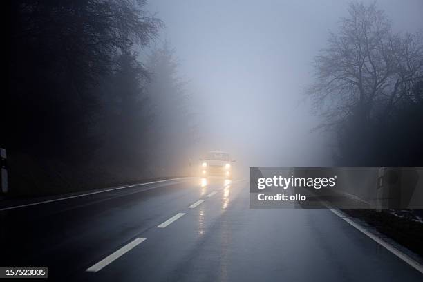 dense fog on the country road, oncoming traffic - foggy road stock pictures, royalty-free photos & images