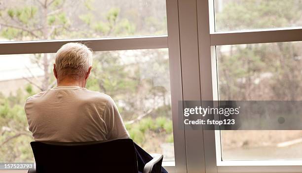 hospital patient waiting by a window. senior adult man. depression. - waiting stockfoto's en -beelden