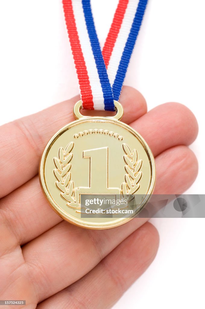 Hand holding a gold medal with ribbon