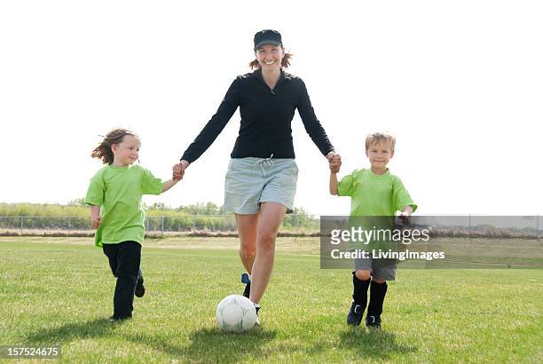 a mom playing soccer with her two children  - soccer mom stock pictures, royalty-free photos & images