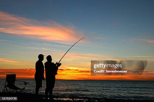 a silhouette of two men fishing at sunset - fishing australia stock pictures, royalty-free photos & images