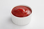 White dip cup filled with ketchup on white background 
