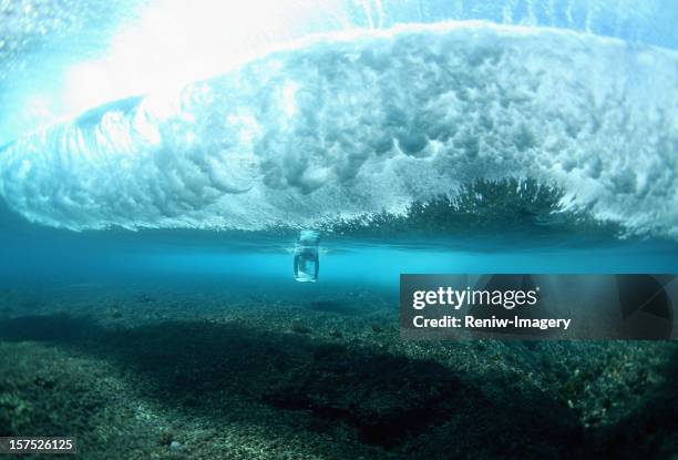 surfer dives underneath a breaking wave - pipeline wave stock pictures, royalty-free photos & images