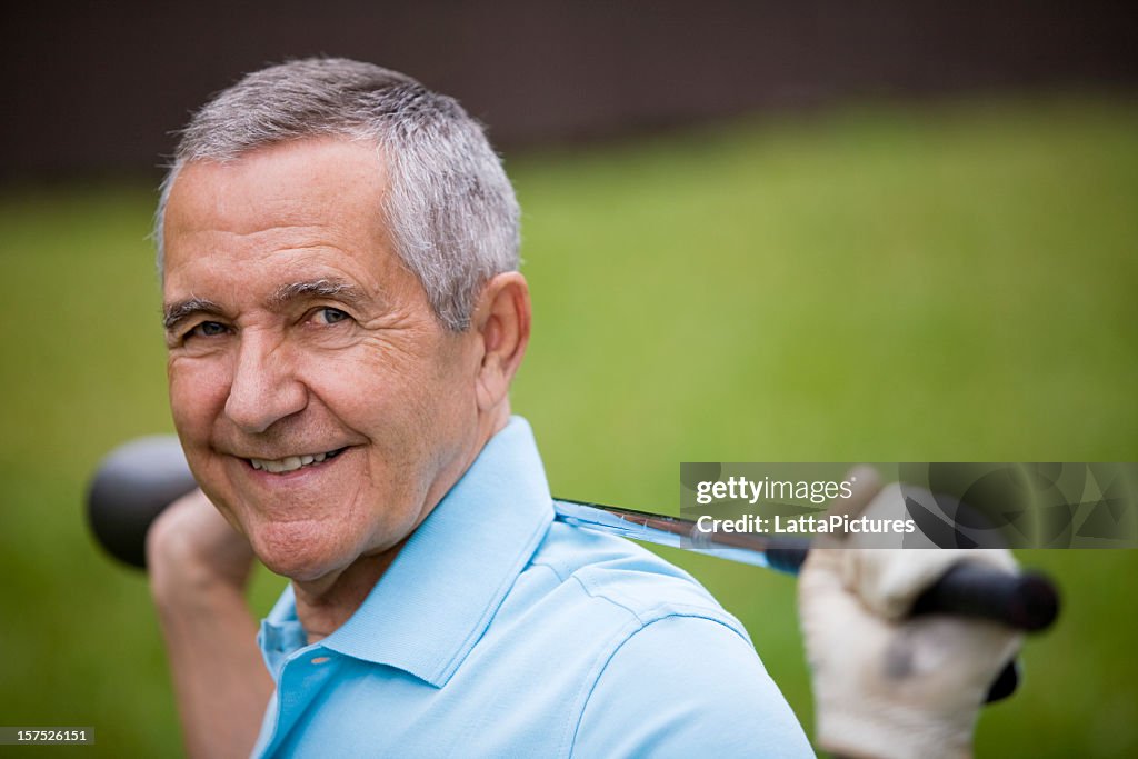 Senior homme tenant golf club derrière le dos