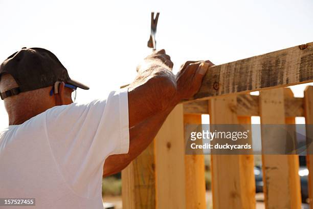 building a fence series - hammering - picket fence stockfoto's en -beelden