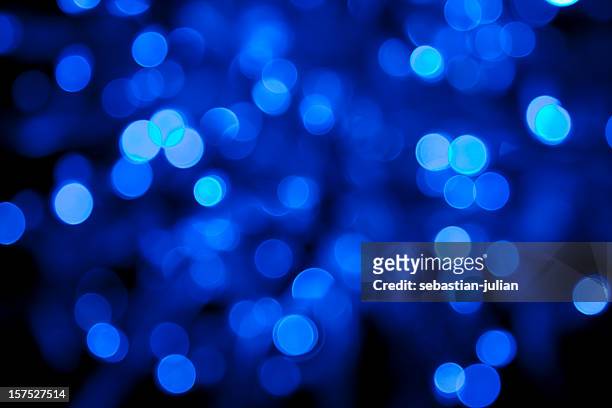 defocused blue light dots against black background - blue christmas background stock pictures, royalty-free photos & images