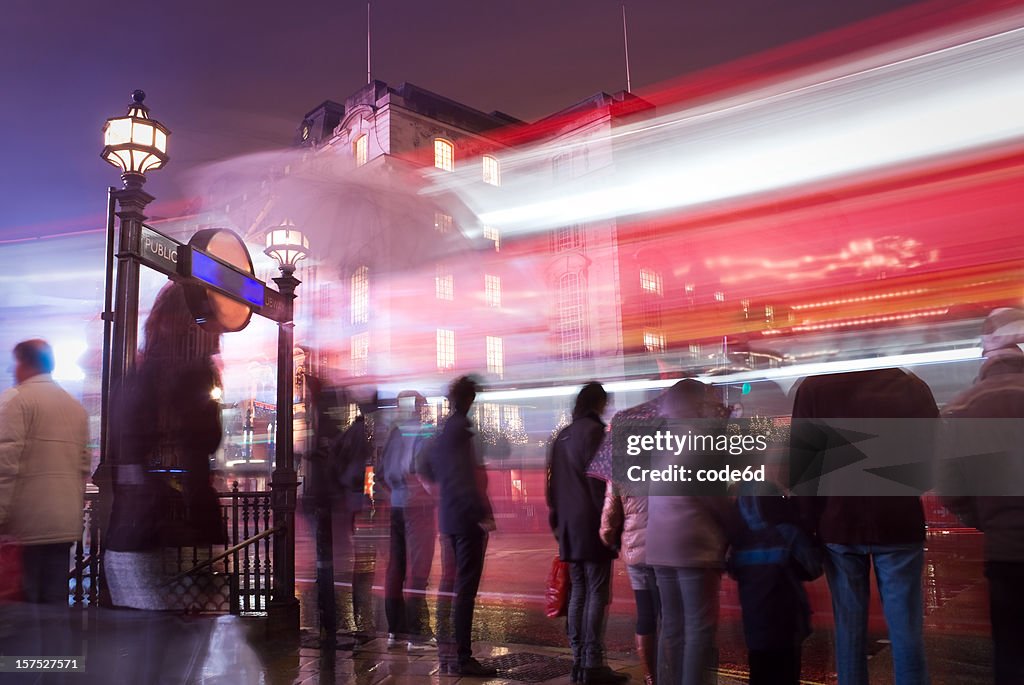 Peões em Piccadilly Circus, Londres, em uma noite de chuva