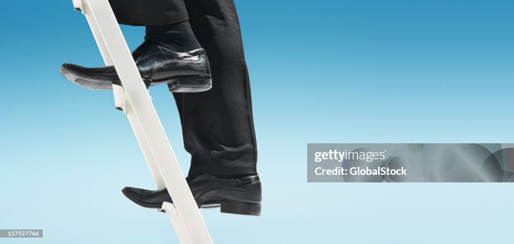 Feet of businessman climbing ladder