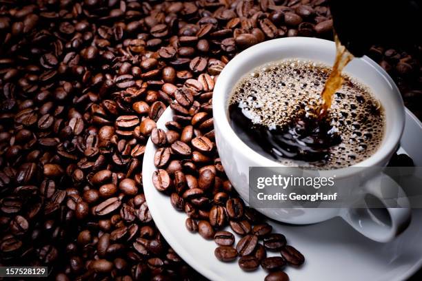 mug on plate filled with coffee surrounded by coffee beans  - roasted coffee bean stock pictures, royalty-free photos & images