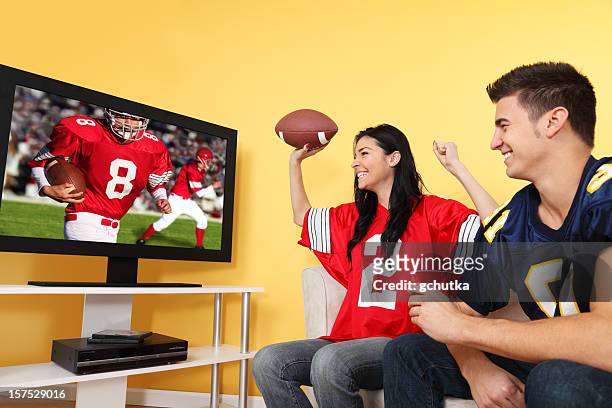 two football fans cheering on a game while they watch on tv - american football tv stock pictures, royalty-free photos & images