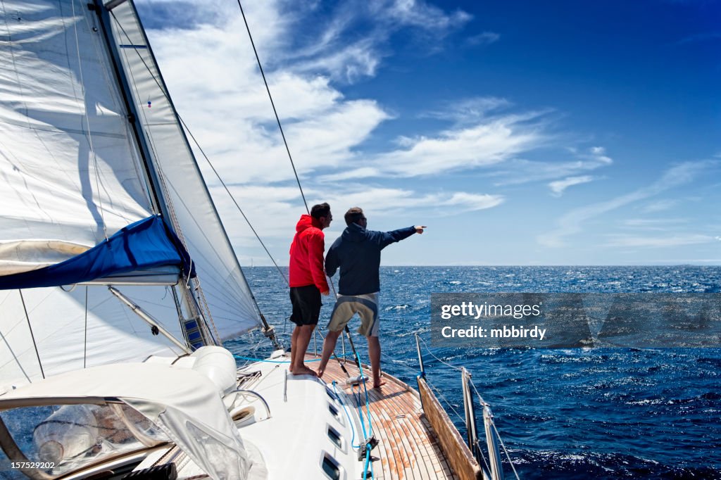 Sailing crew on sailboat observing the sea