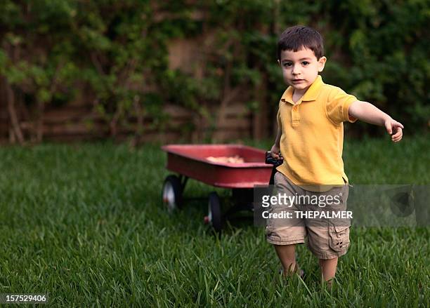 small kid pulling a red wagon - toy wagon stock pictures, royalty-free photos & images